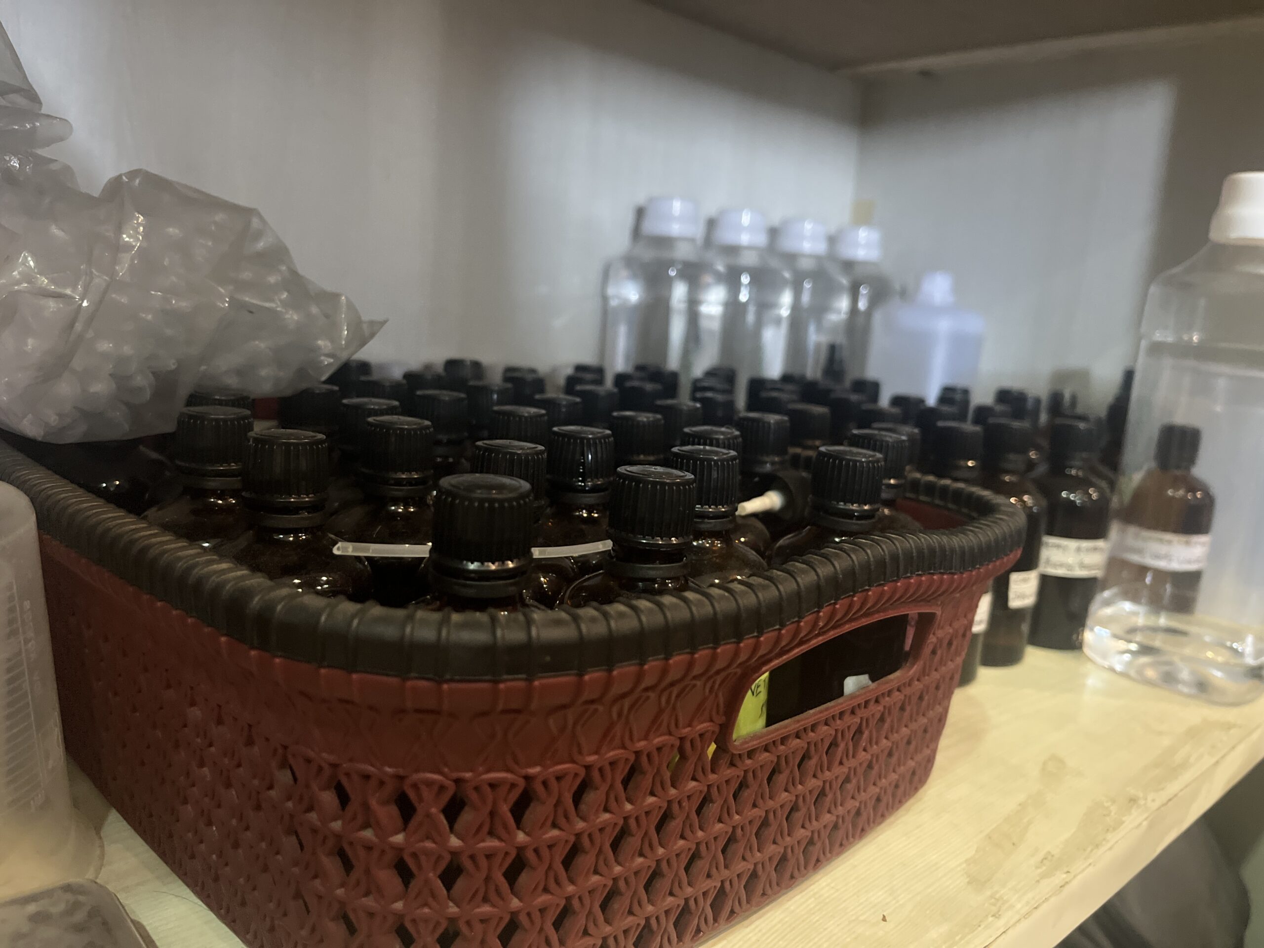A shelf inside the early home studio of Bois et Fleurs Parfums, showing dozens of amber glass bottles and perfumery materials. This image captures the humble beginnings of an independent Indian perfume brand focused on handcrafted, small-batch fragrances for Indian skin and climate.